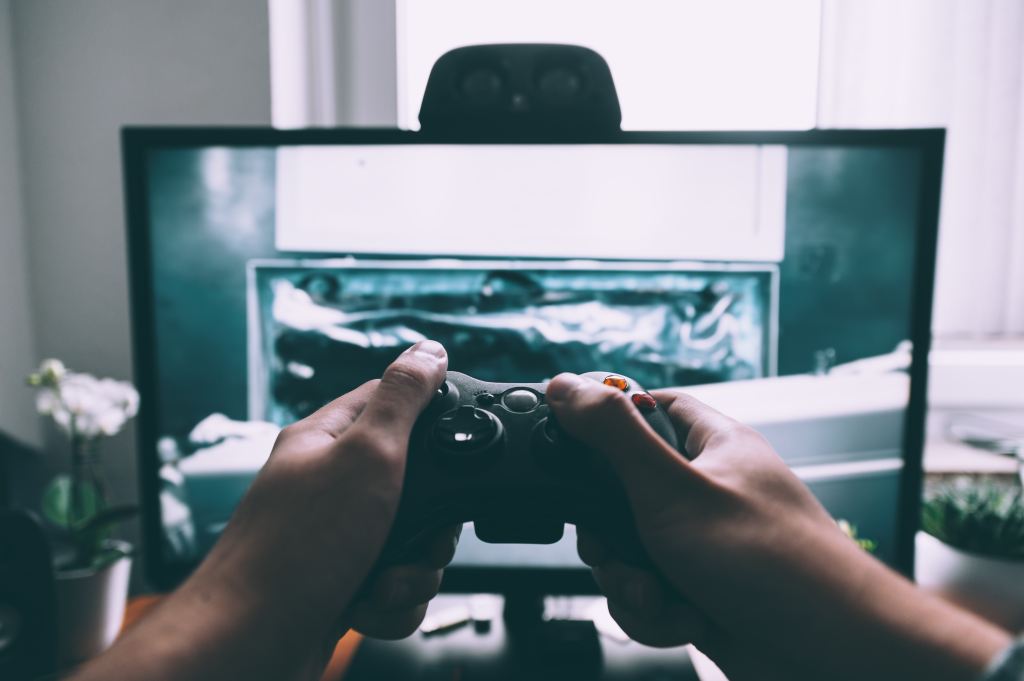 Player using black Xbox controller in front of a TV